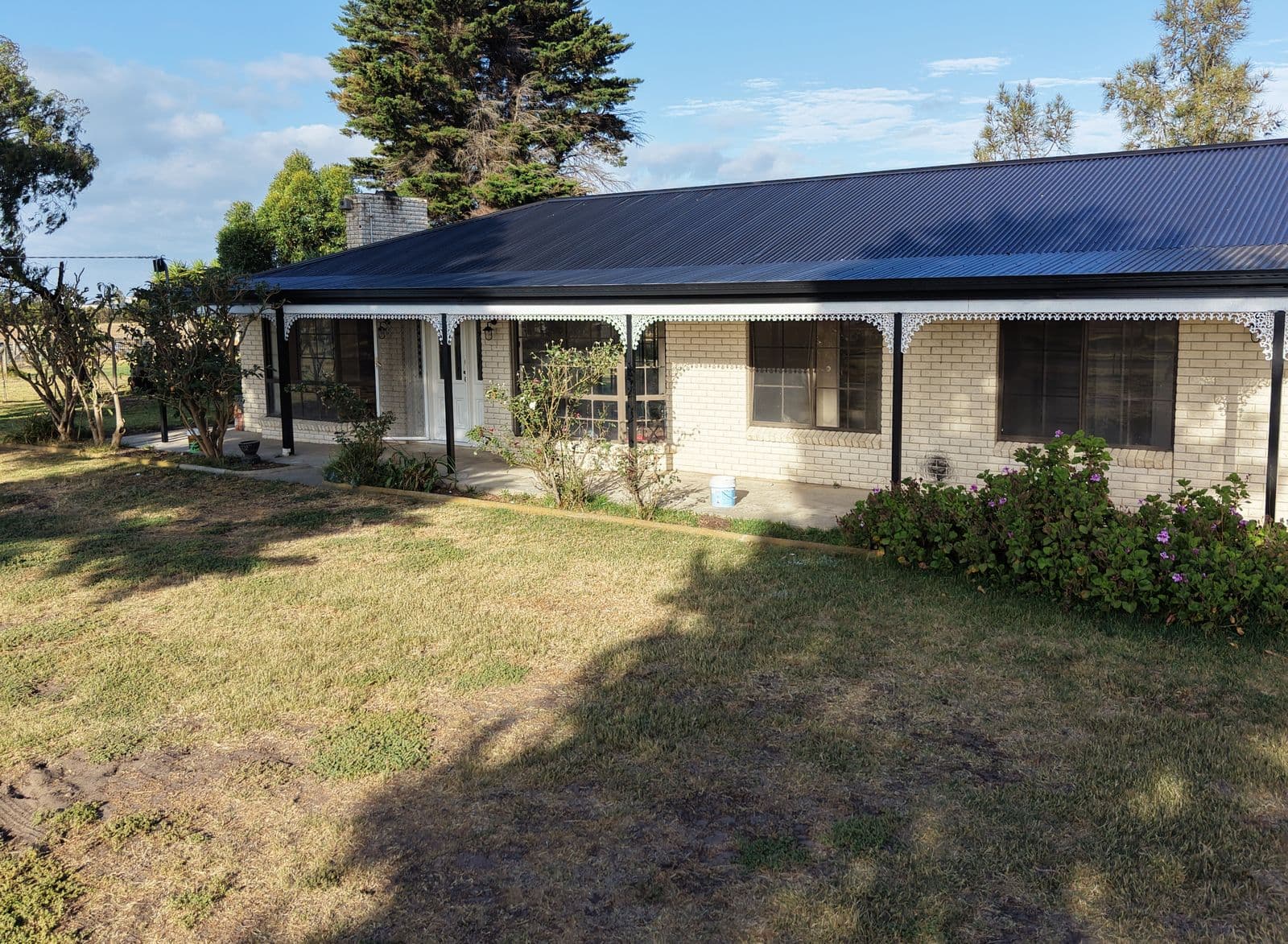 Aerial view of a brick home with black posts and fascia and white verandah lacework